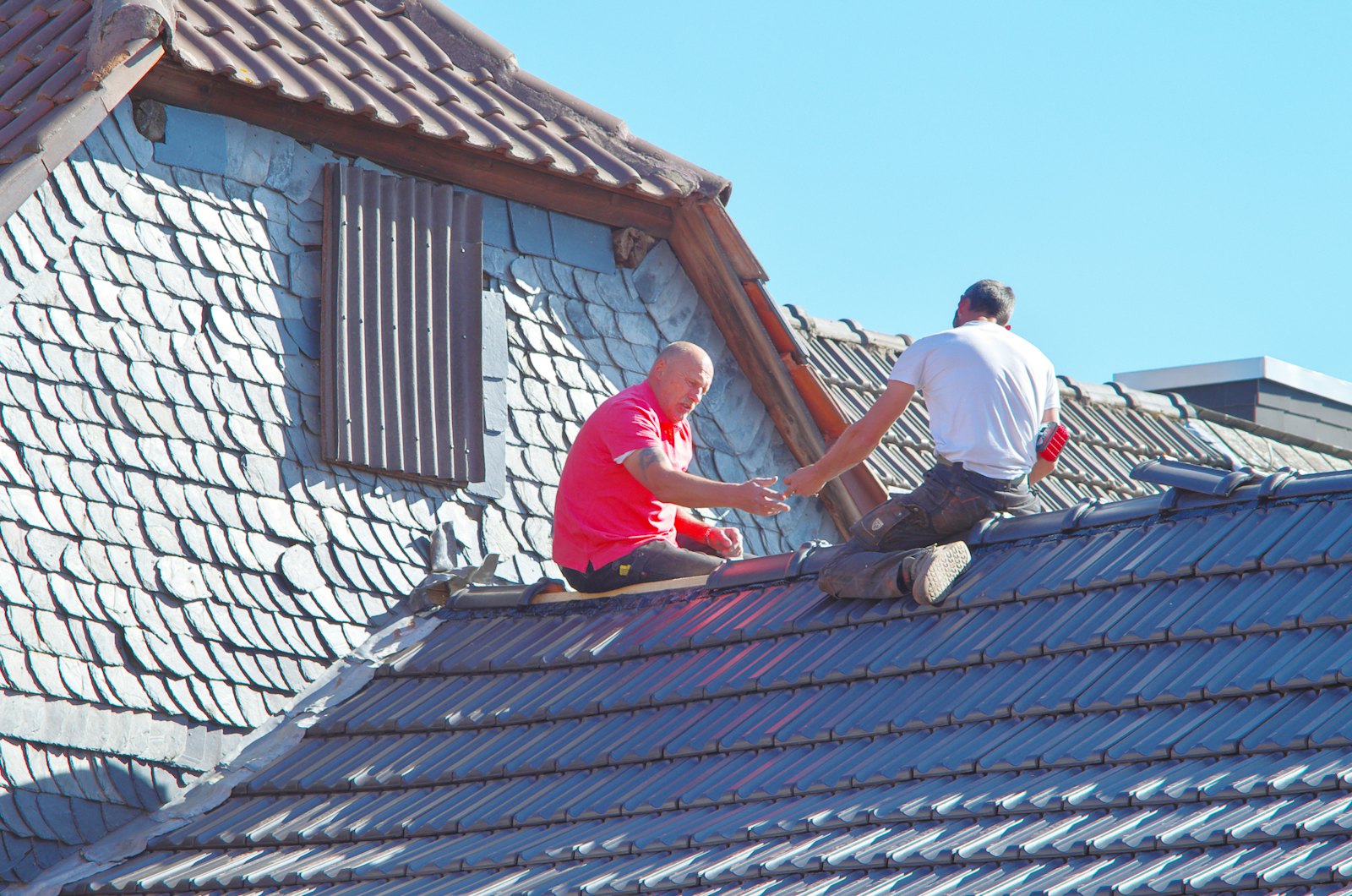 Roofers working on a pitched slate roof